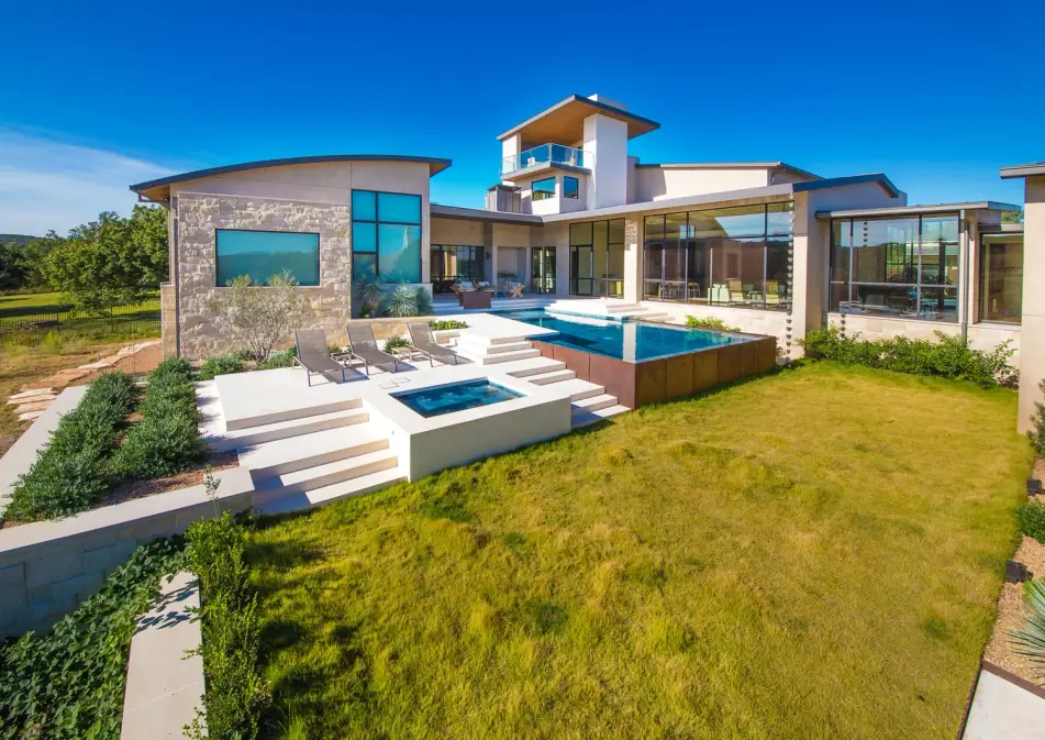 Hill Country contemporary home with a raised infinity-edge pool and spa above a lawn
